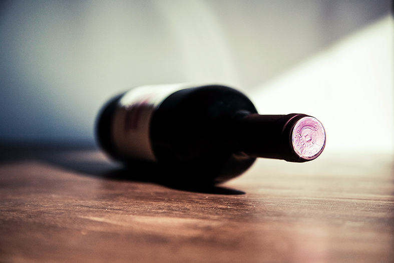 Garrafa de vinho deitada em mesa de madeira.